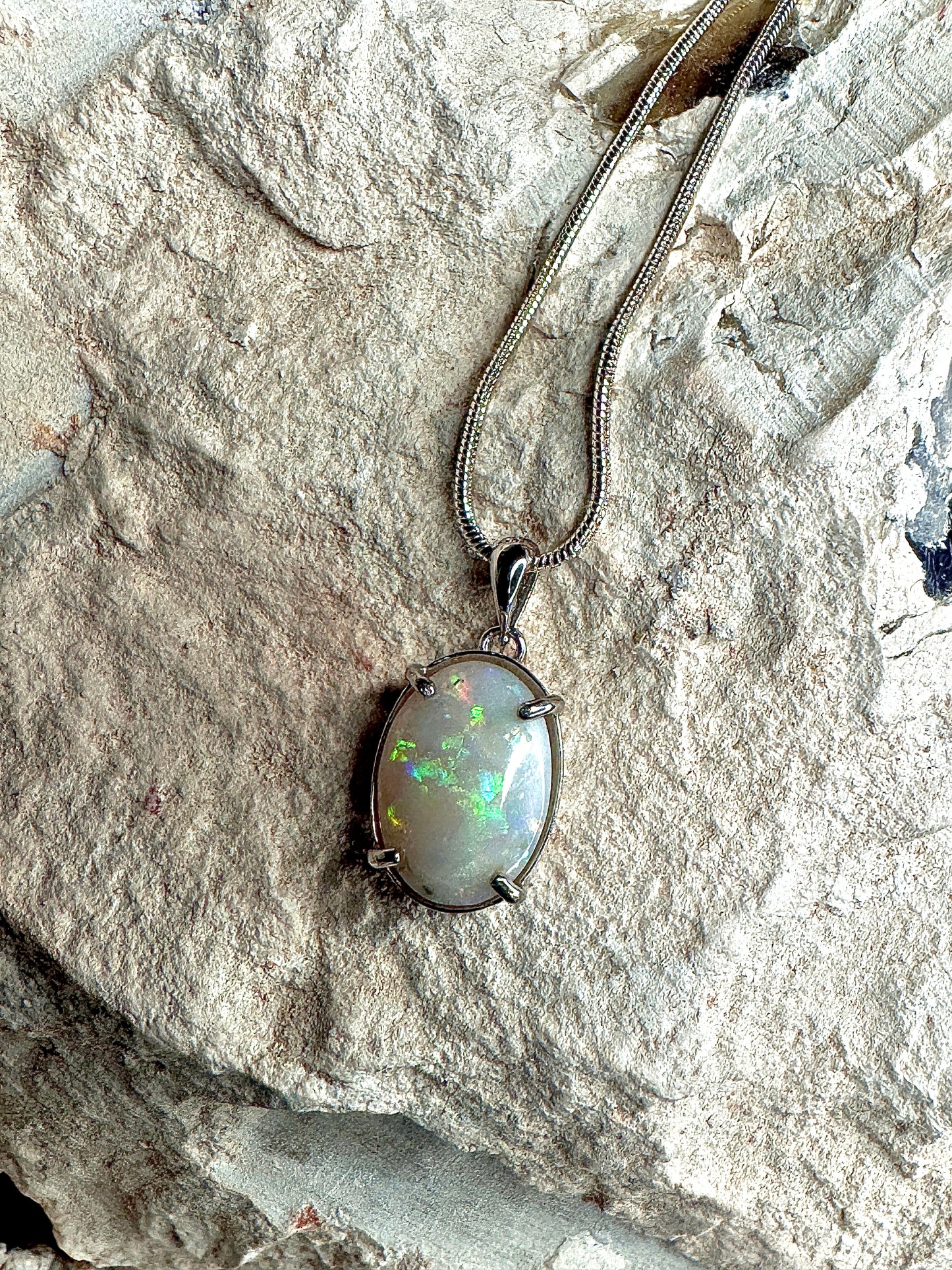 Opal pendant necklace on a stone surface