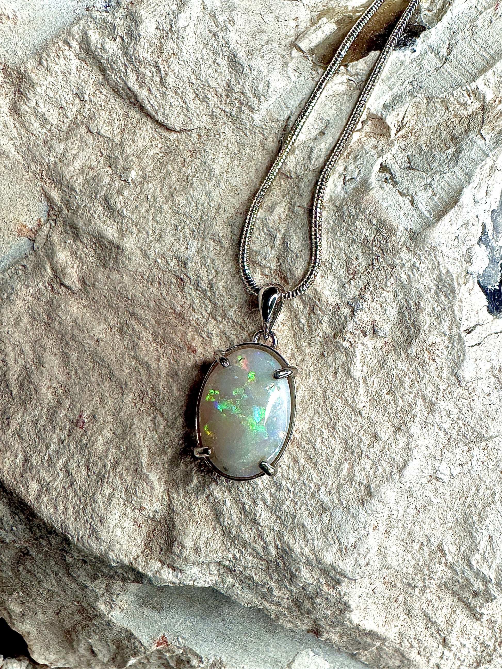 Opal pendant necklace on a stone surface